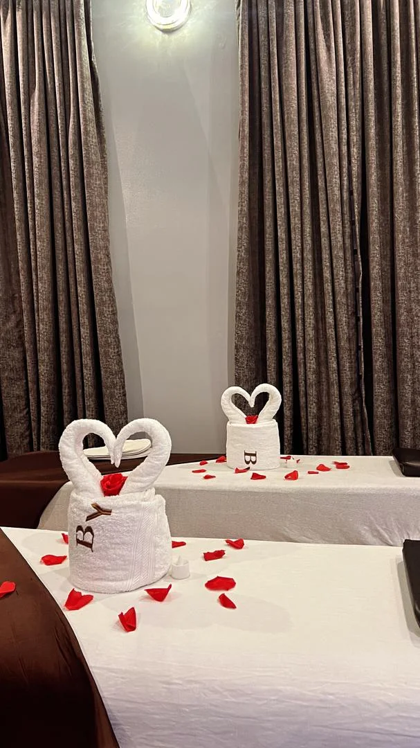 Towel swans and rose petals on a massage bed